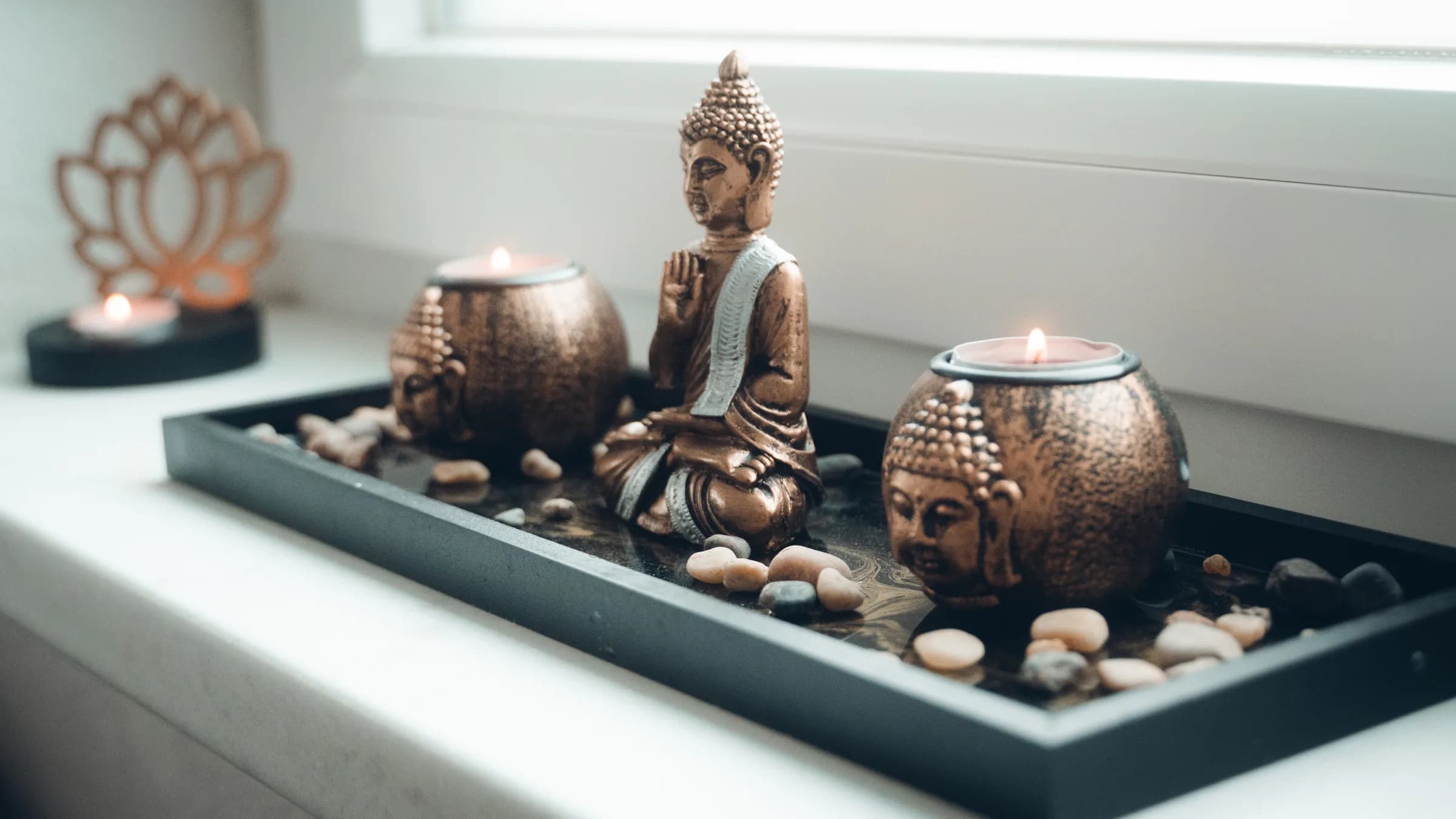 Buddha-Figur zwischen zwei Teelichtern auf der Fensterbank des Behandlungsraums